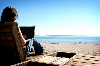 iWork vs. Microsoft Office: An image woman works with a laptop on a beach.