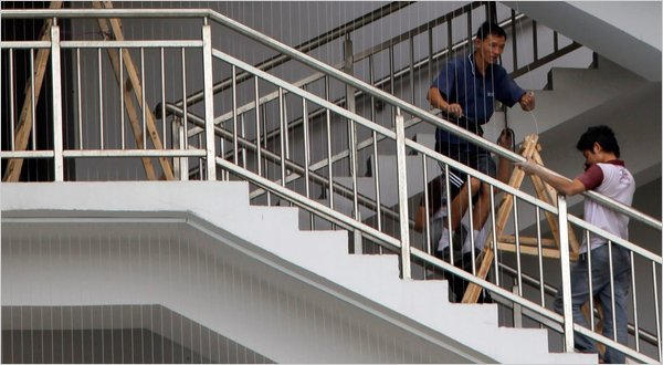 Workers install suicide netting at a Foxconn plant. Image: NYT.