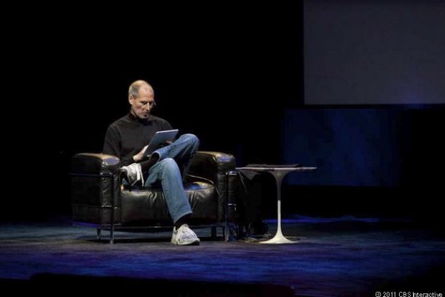 Steve Jobs reclines in a chair on stage to show off the iPad.