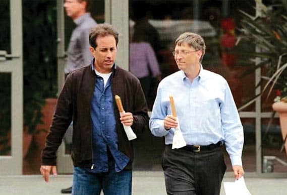 A still from a Microsoft ad shows Jerry Seinfeld eating a churro with Bill Gates outside a shoe store.