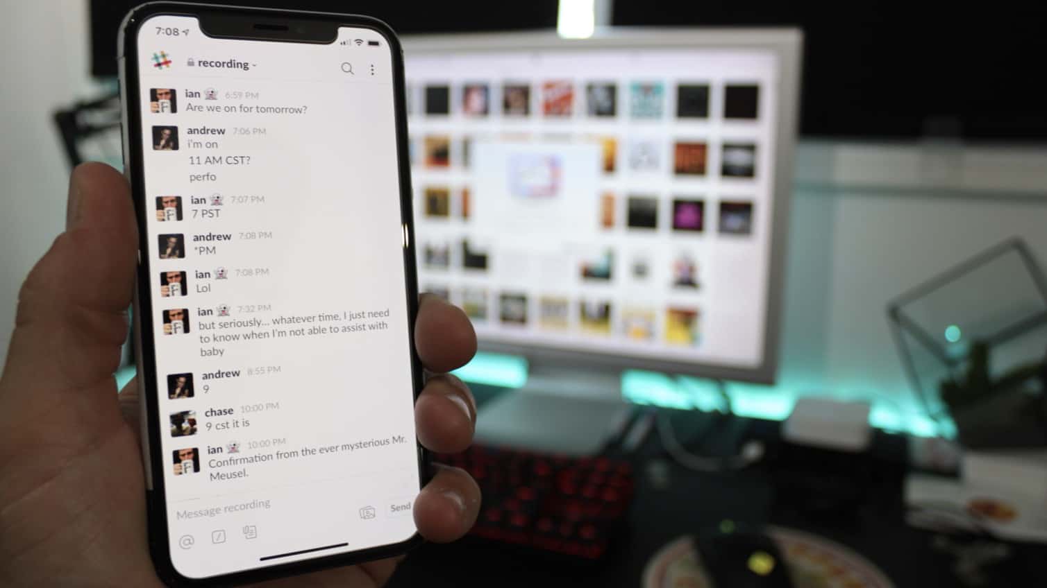 Slack iOS app on iPhone in front of computer
