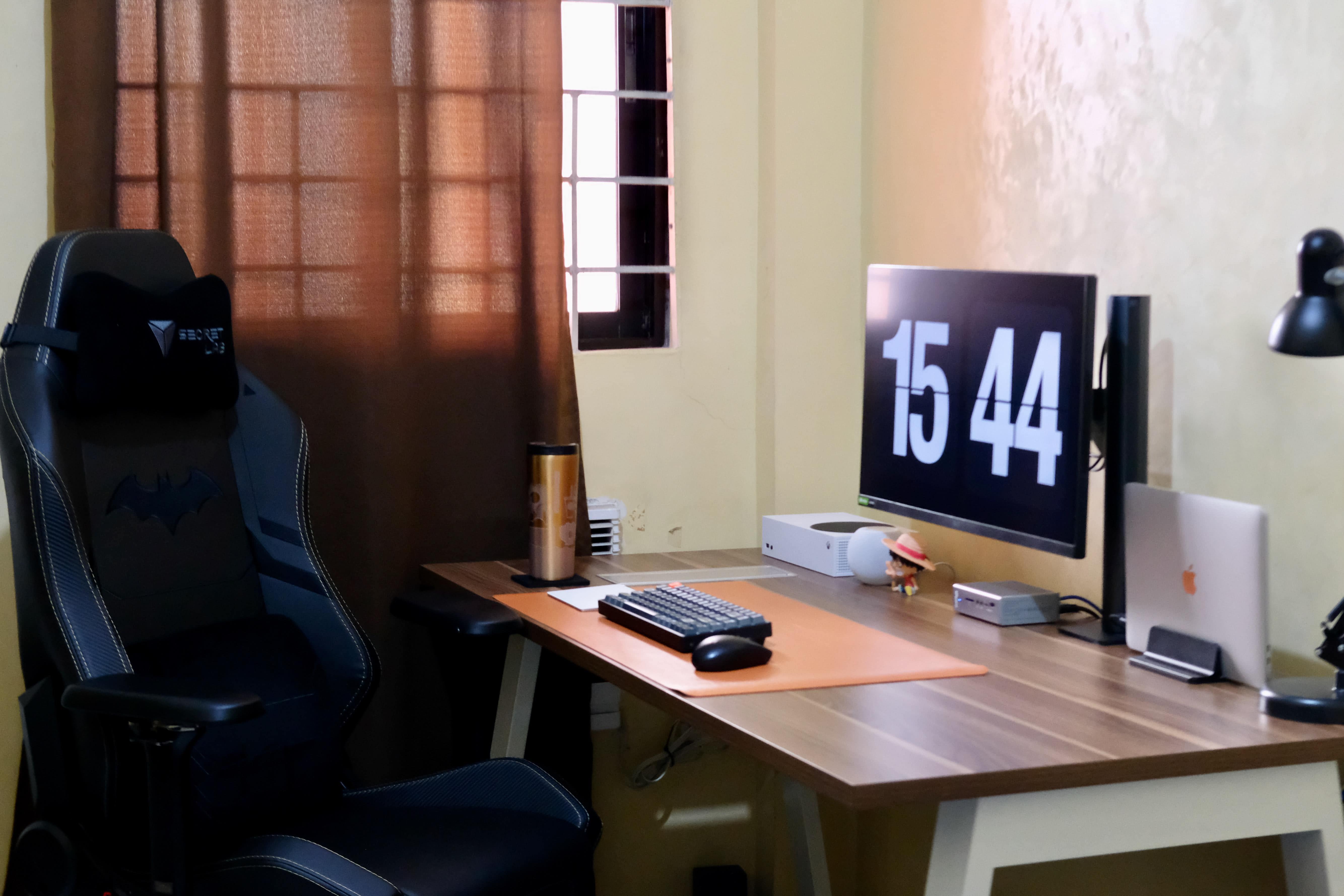 This setup features a tasteful wood-grain desk and a gamer chair fit for Batman.