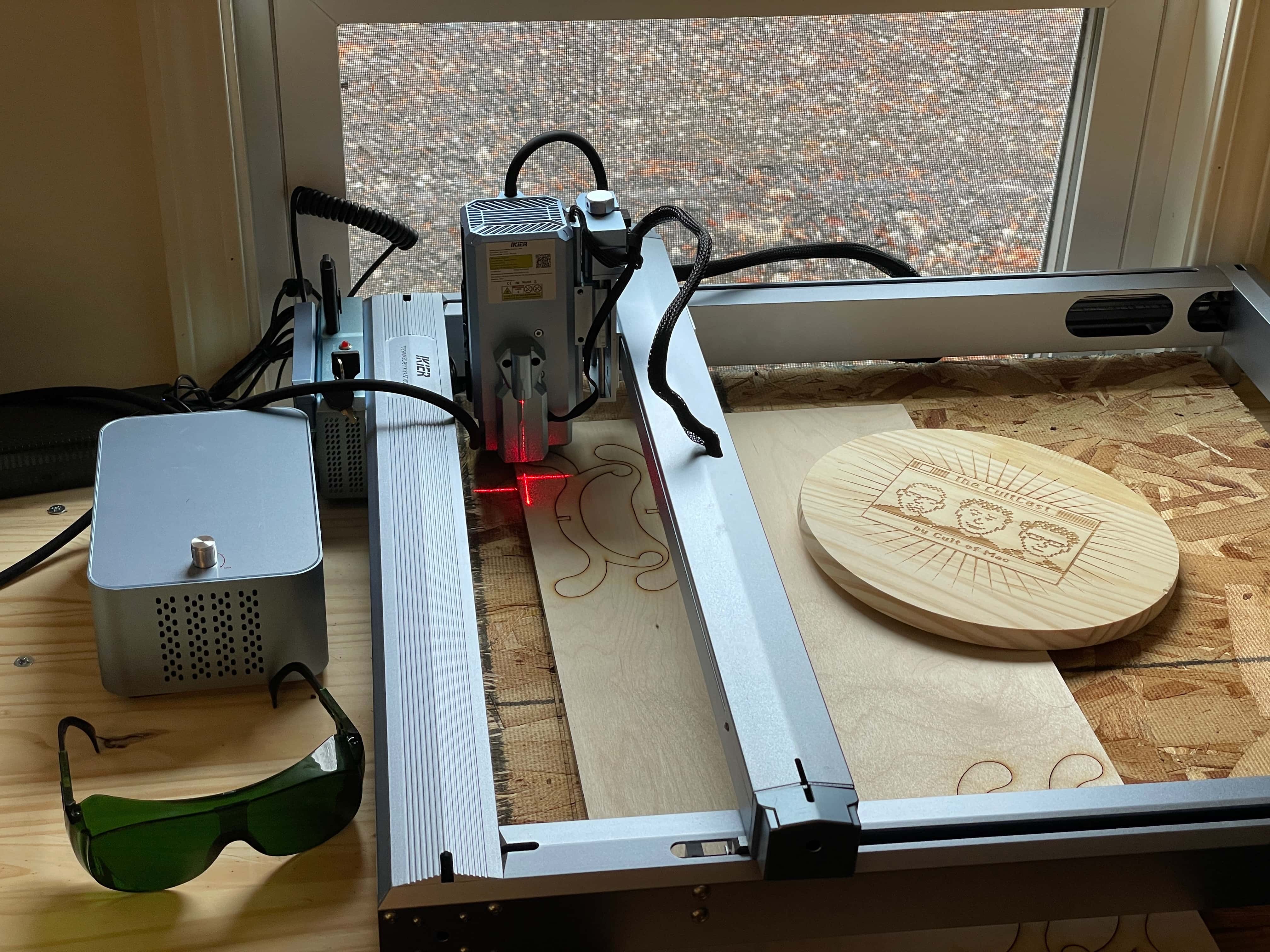 iKier K1 Pro Max laser engraver with a few projects etched into wood sitting beside it