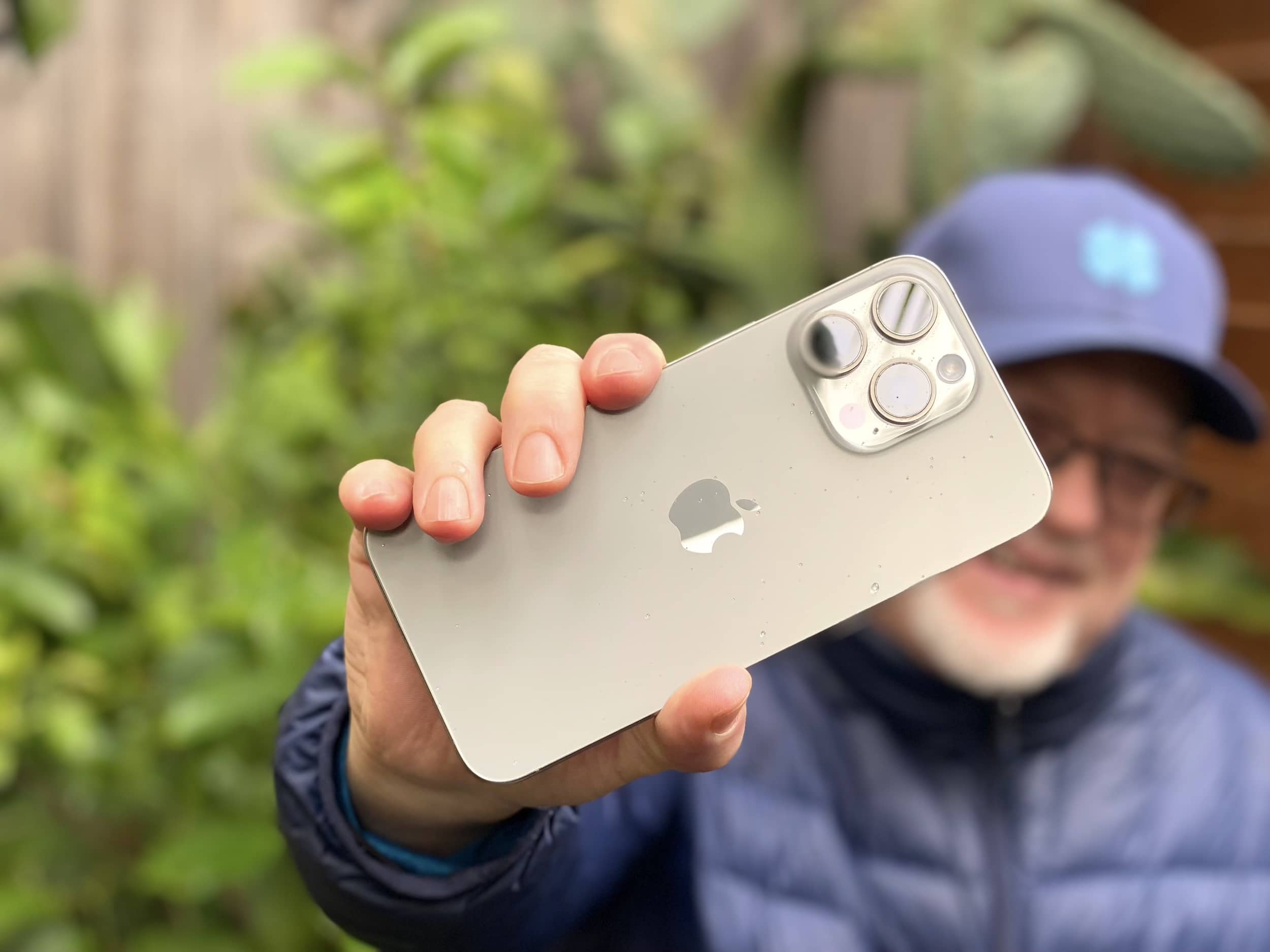 iPhone 15 Pro Max with no case, held aloft defiantly