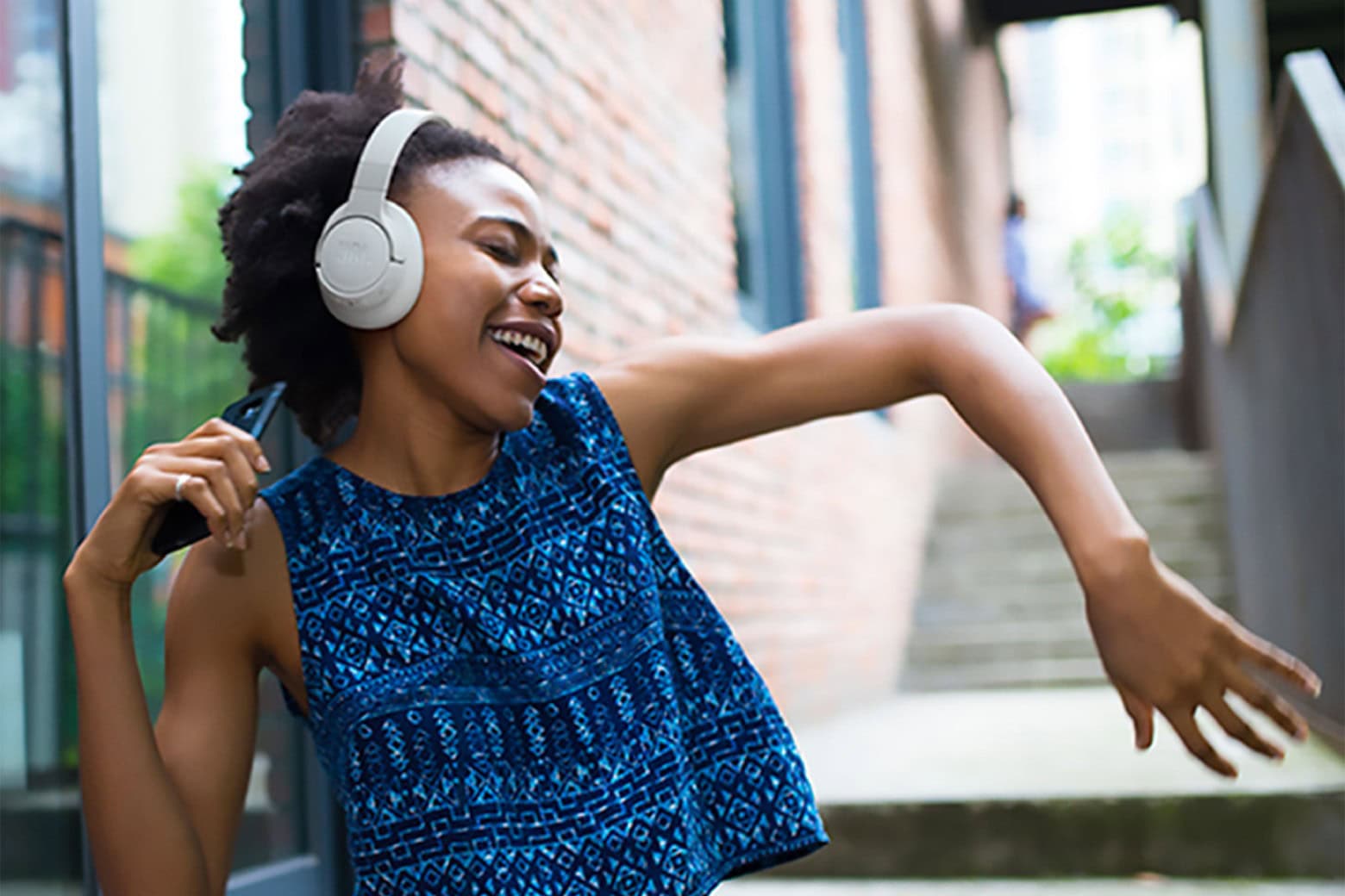 Woman dancing while wearing JBL Tune 770NC over-ear noise-canceling headphones.