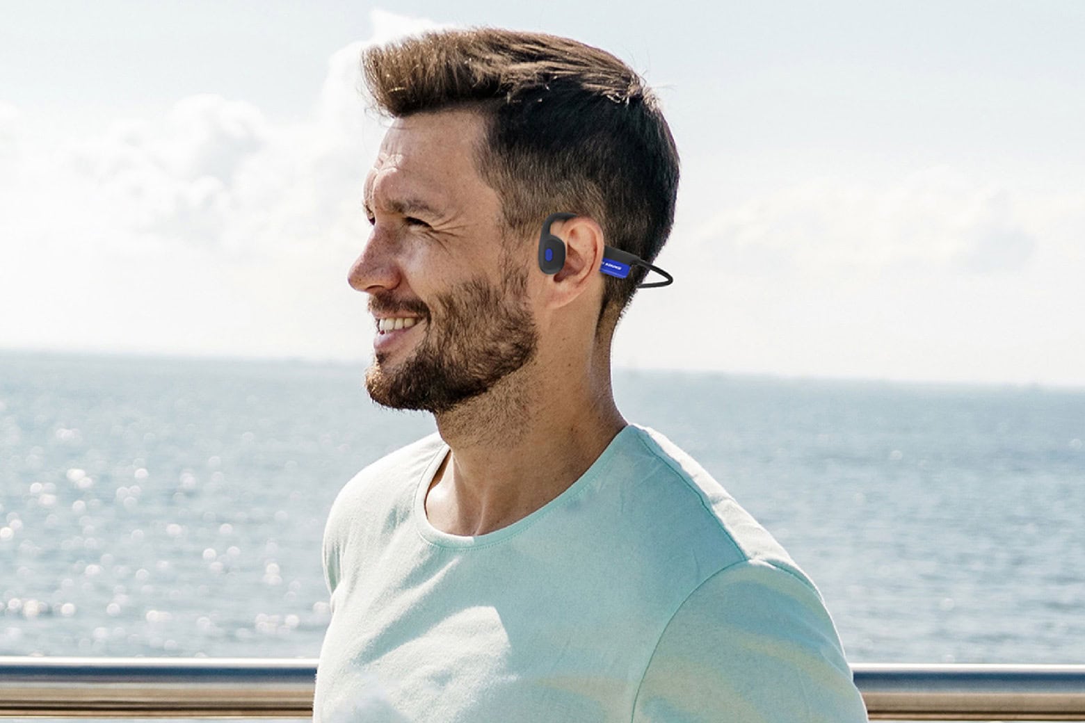 Man wearing Mezzo+ Bluetooth bone-conduction headphones outside on a sunny day