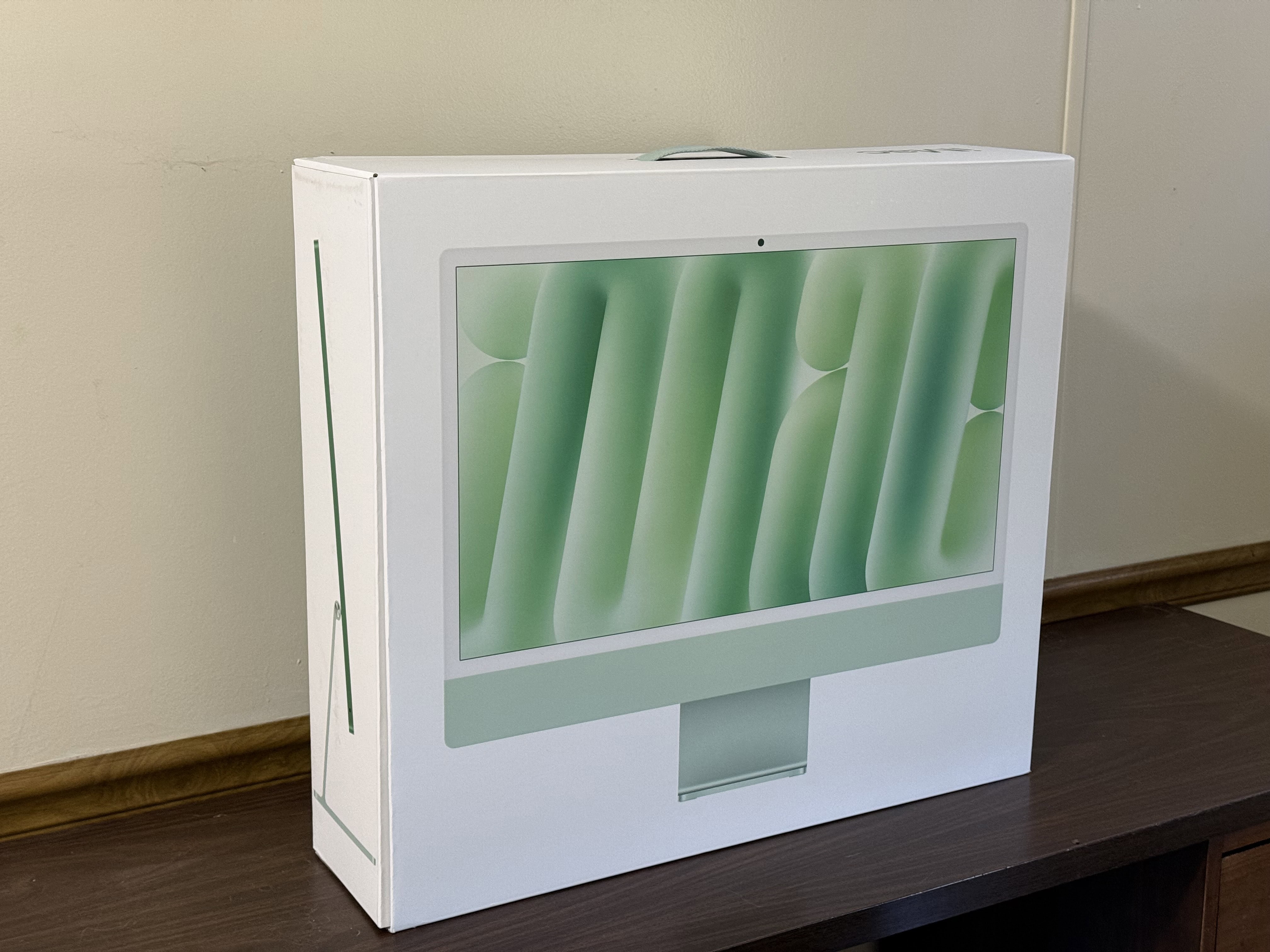 Green iMac box sitting on a brown desk.