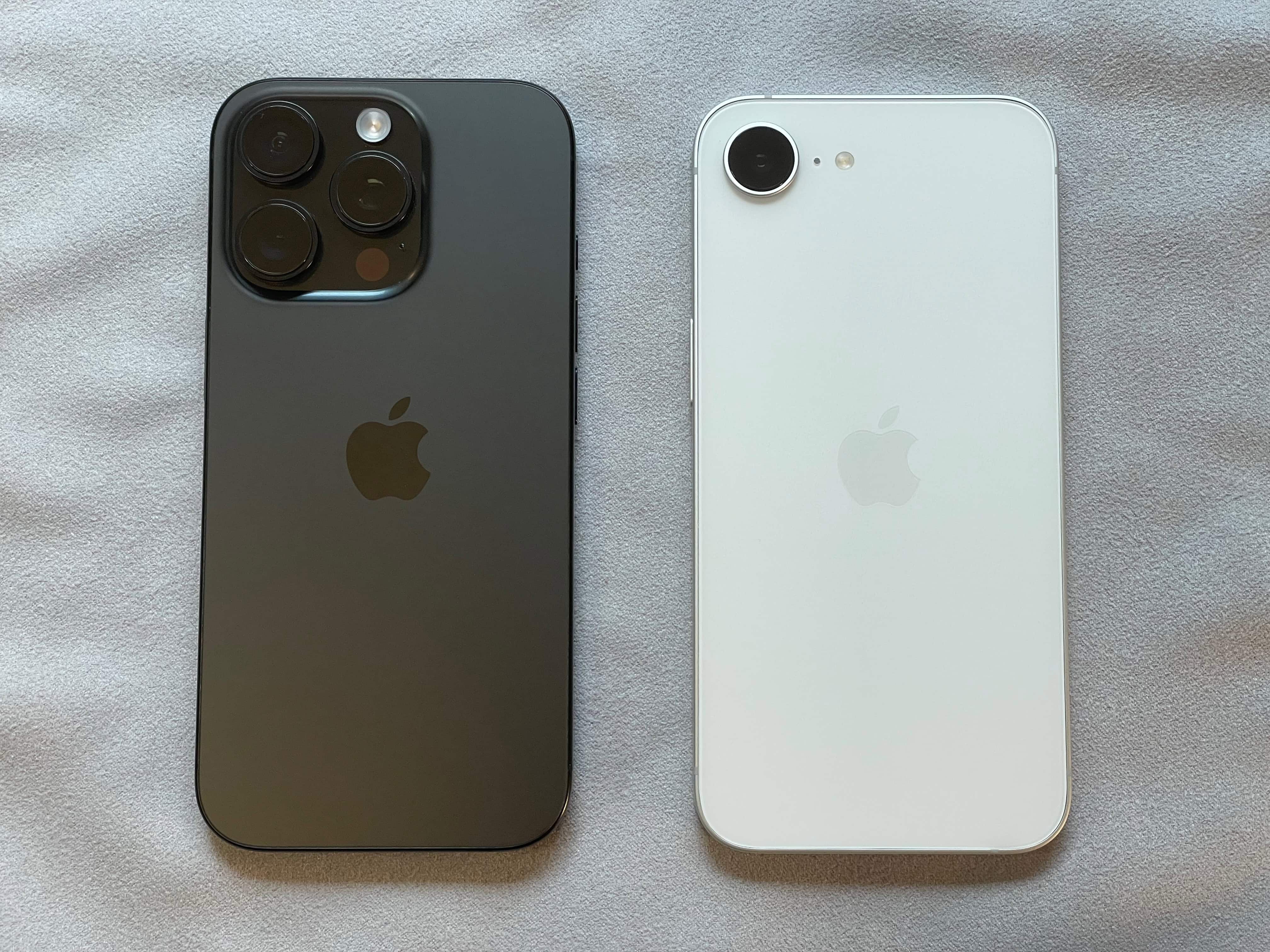 iPhone 16 Pro and iPhone 16e laying side by side, showing the difference in rear camera size.