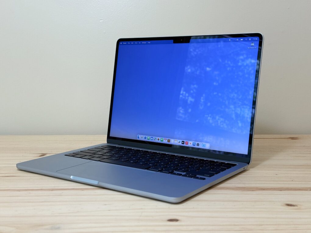 M4 MacBook Air sitting on a pine table, with a window reflecting on its display